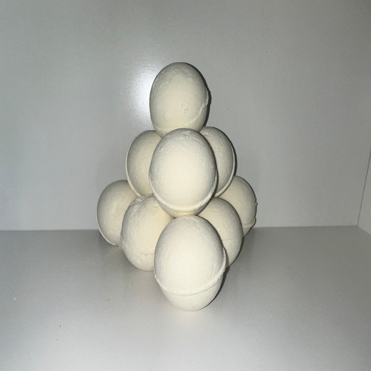 Pyramid of white bath bombs on a white surface with a plain background