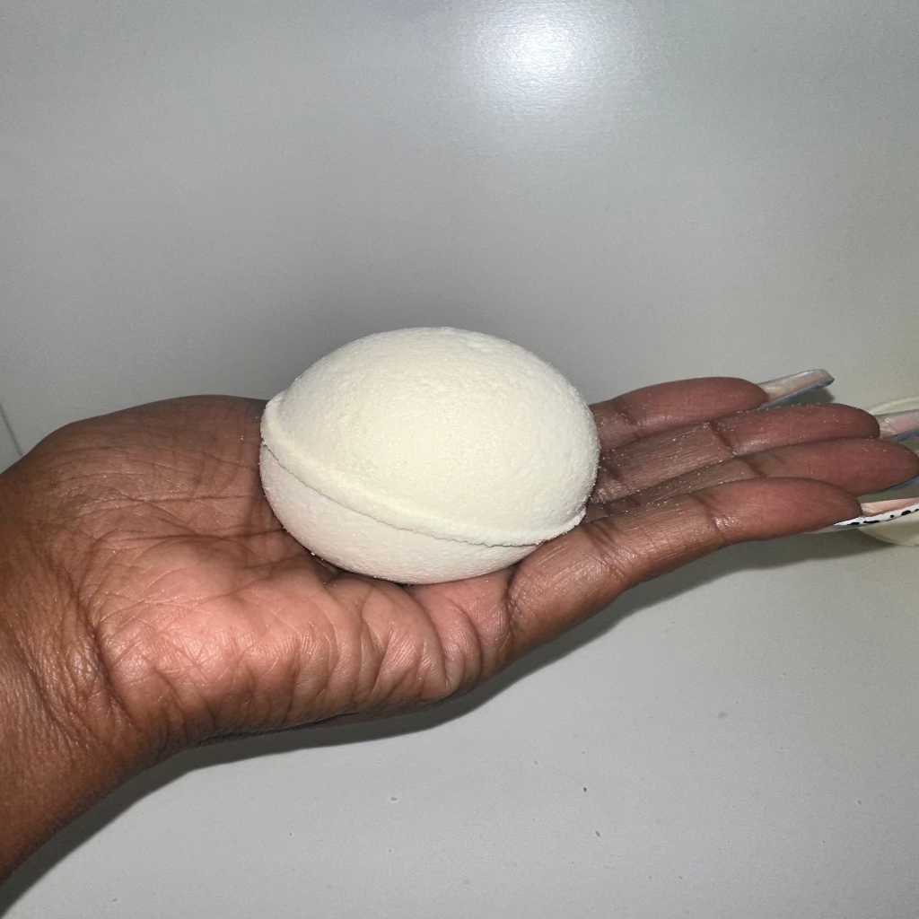 White hair detox bomb held in a hand against a plain background